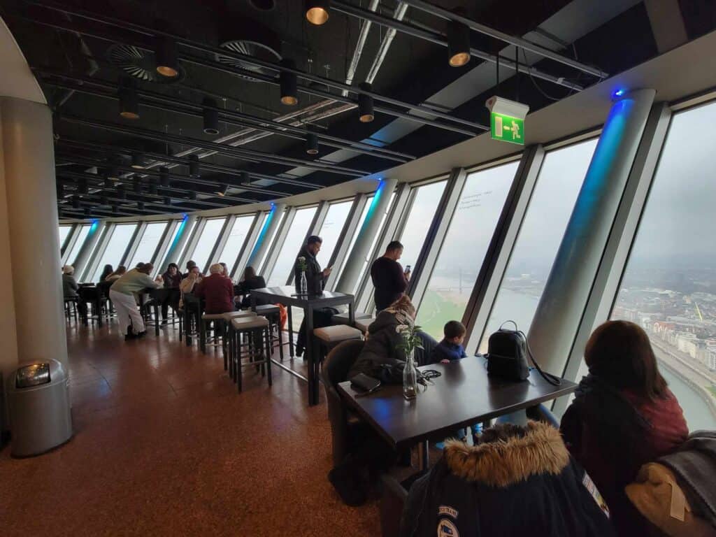 A row of cafe tables nest to slanted windows looking down from a great height