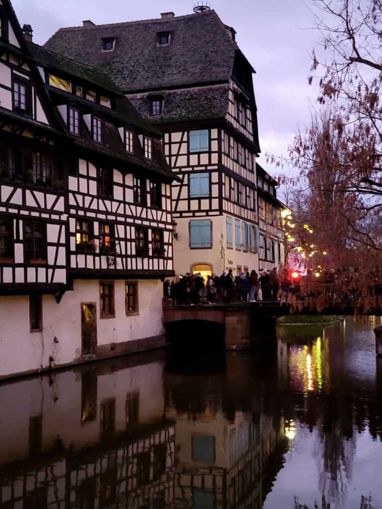 Half timbered buildings next to a canal at dusk