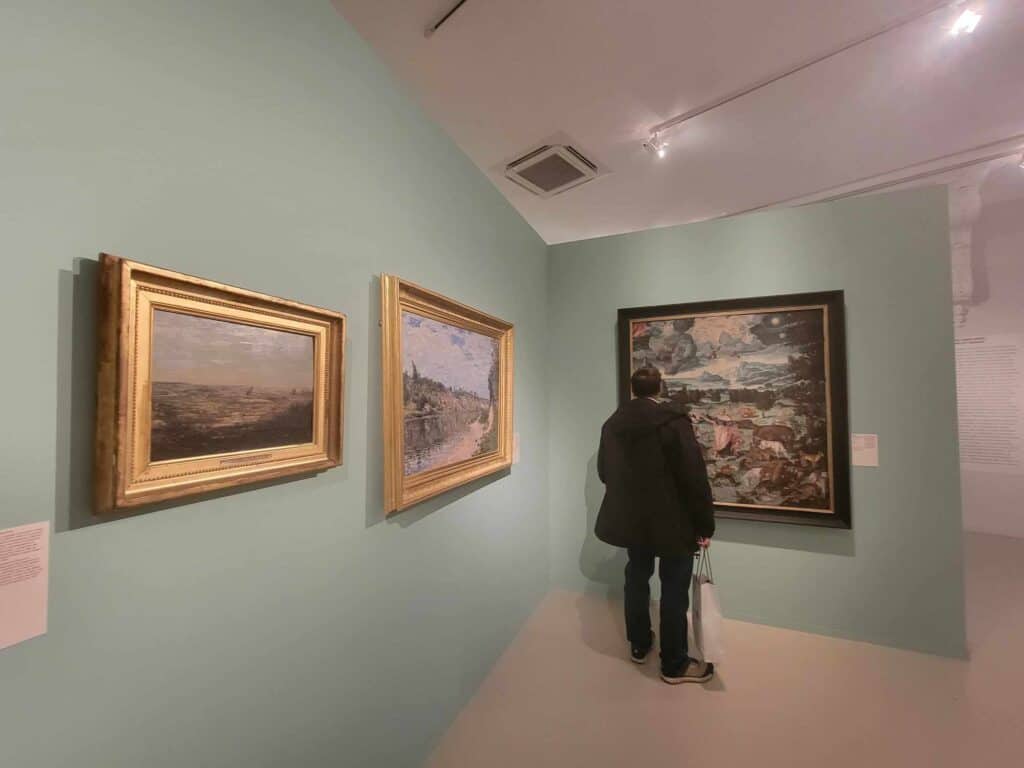 A man in a museum looking at a landscape painting