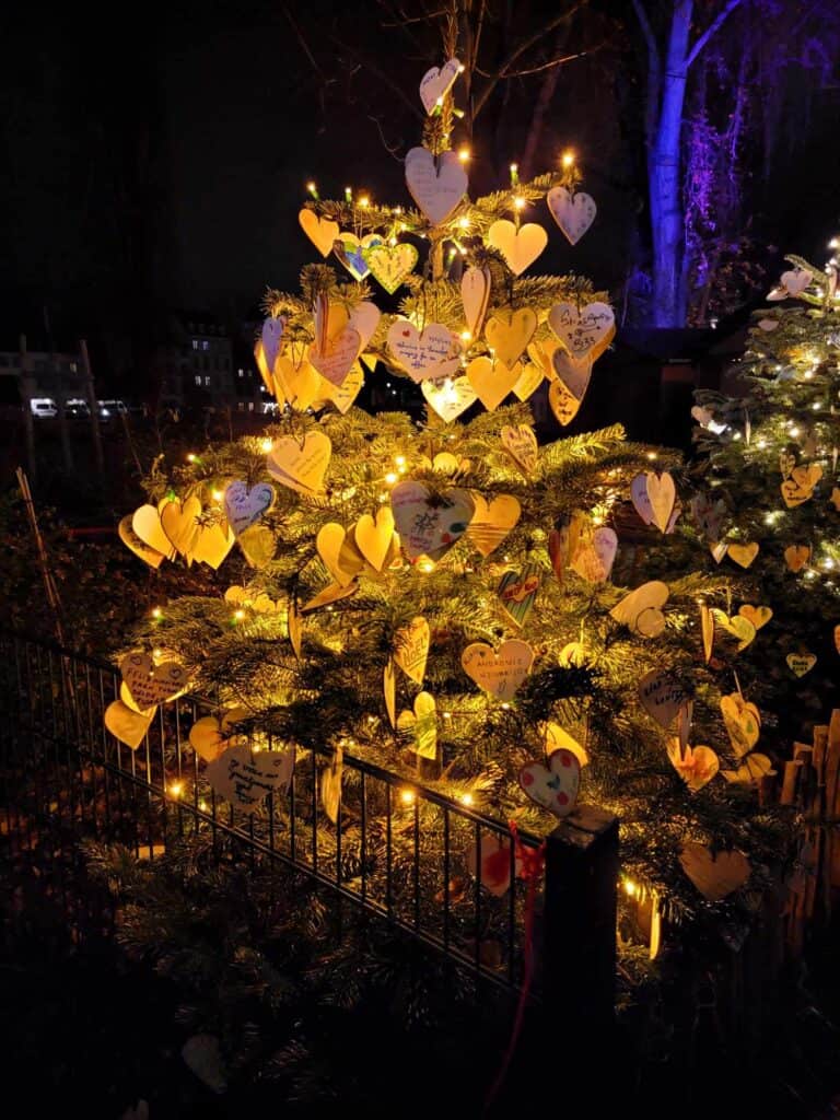 A tree illuminated in gold light with heart shaped ornaments