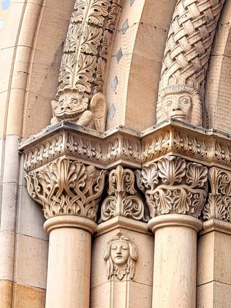 An ornate architectural element on an arch with three gargoyle faces