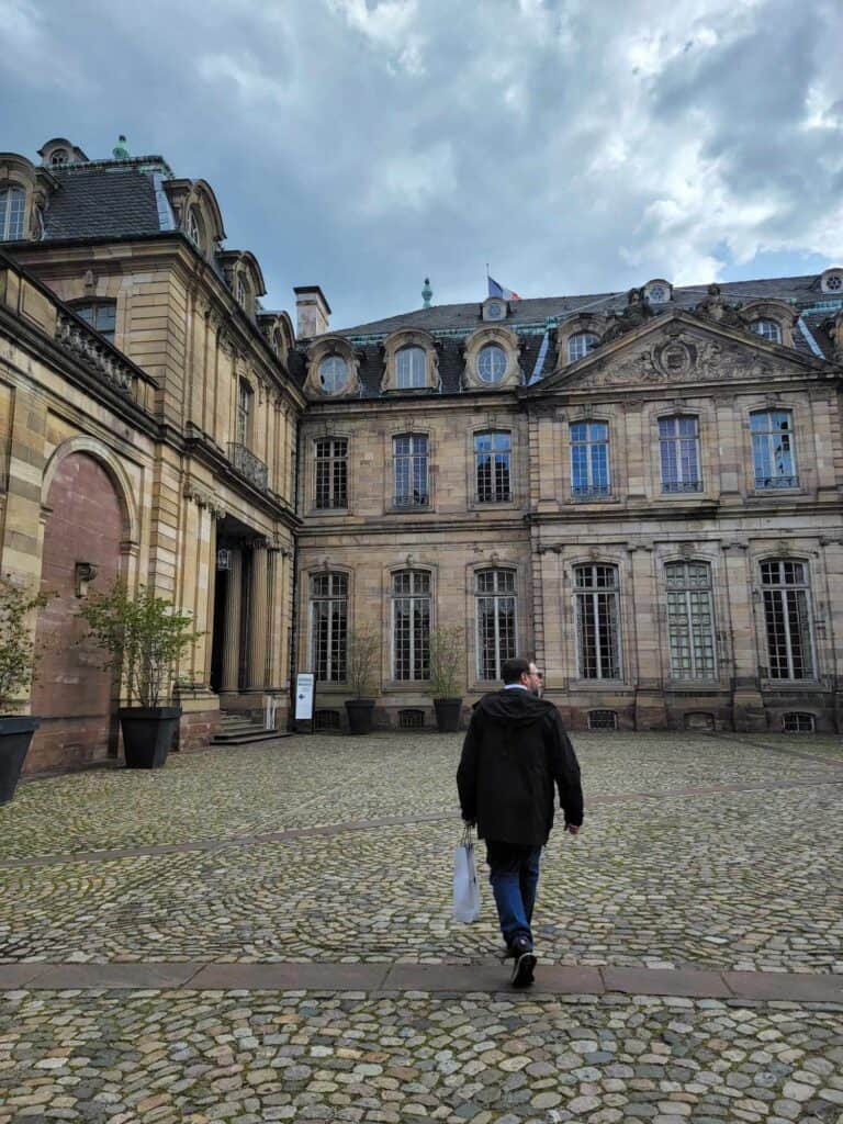 A man walking in a cobblestone courtyard toward the entrance to the museum in Palace Rohan