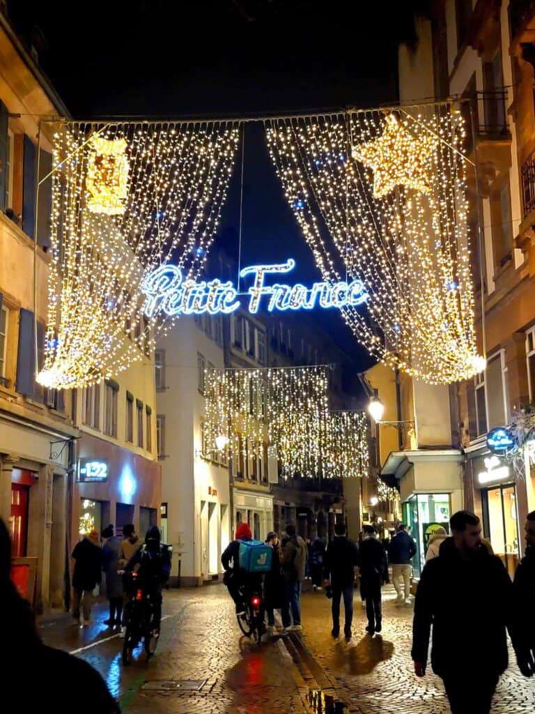 A curtain of little white lights and stars with Petite France spelled out