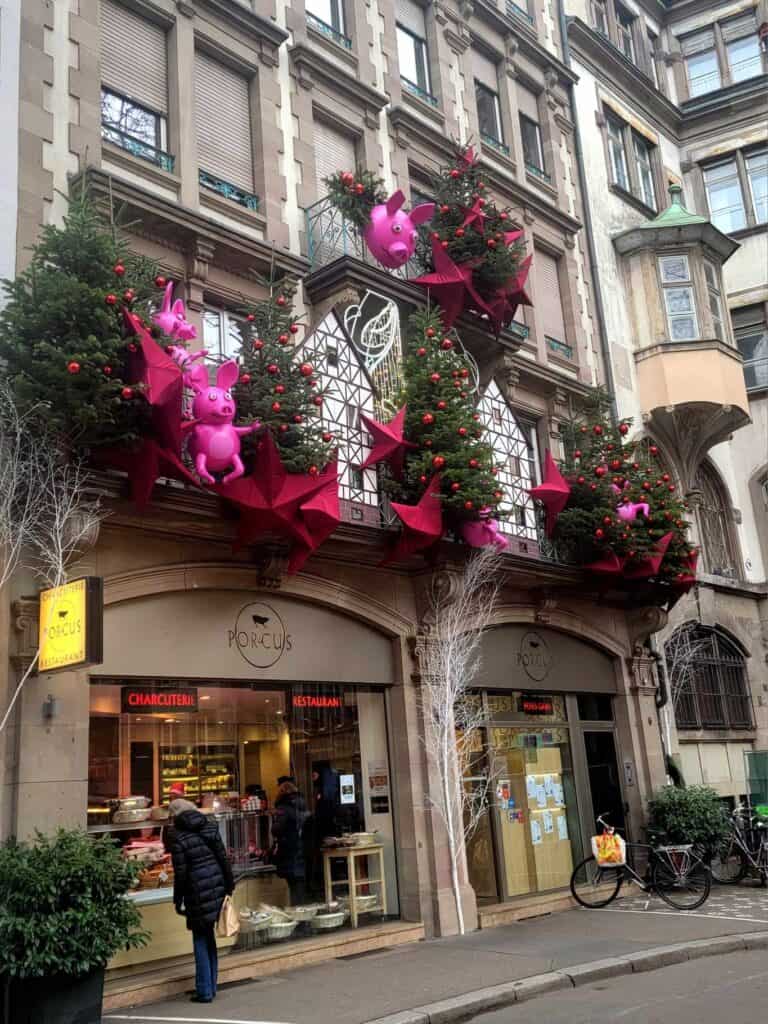 A charcuterie shop with huge christmas decorations including bright pink pigs