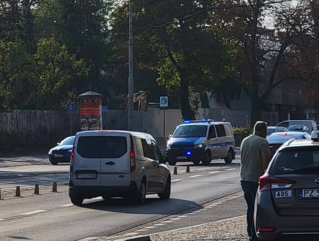 A police van with blue lights driving down the street in Poznan