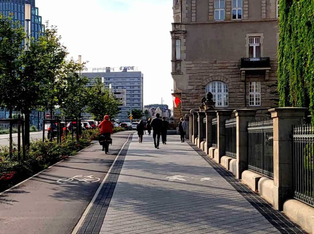 Two lanes, a bike land marked by a white bicycle painted on the ground on the left, and a pedestrian lane marked by walking figures on the right in Poznan