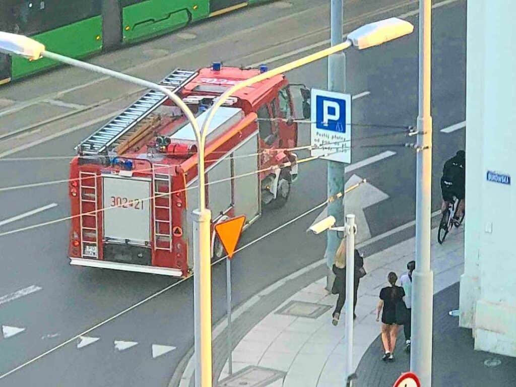 A fire engine passes pedestrians on the street