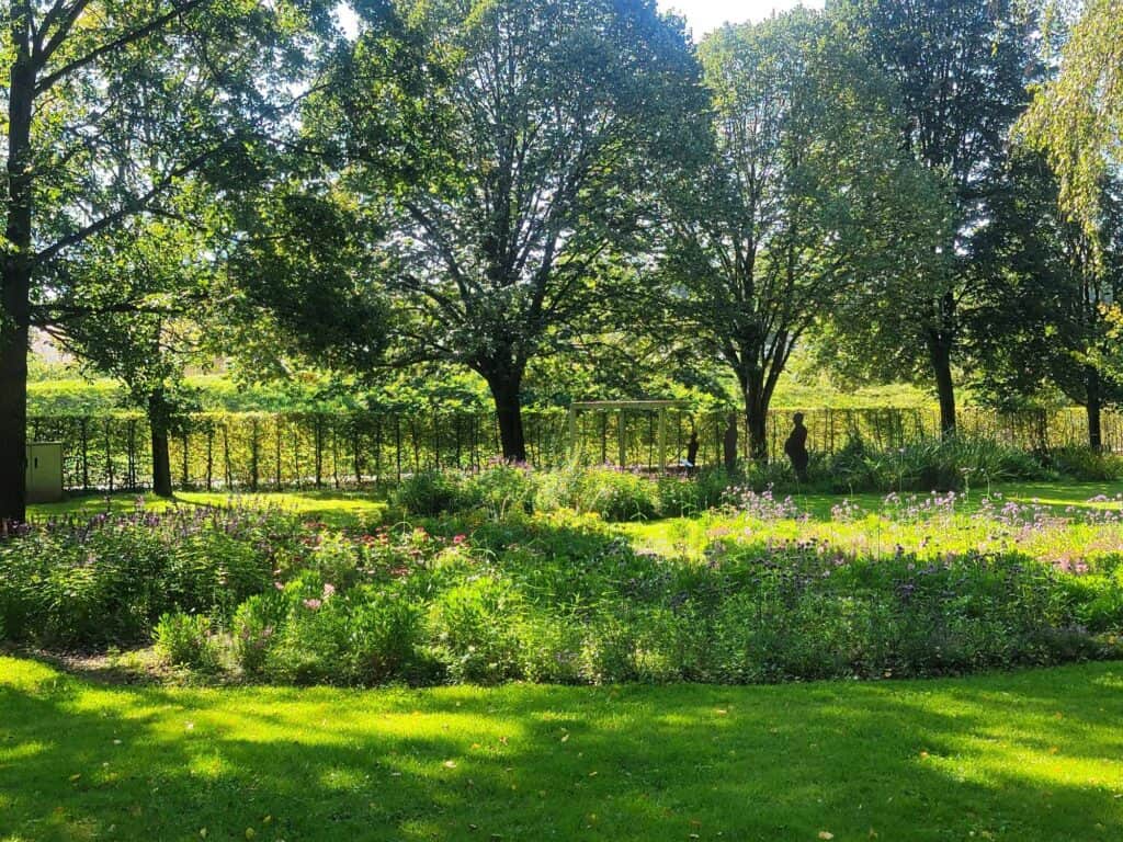 A flower bed, green grass, green trees