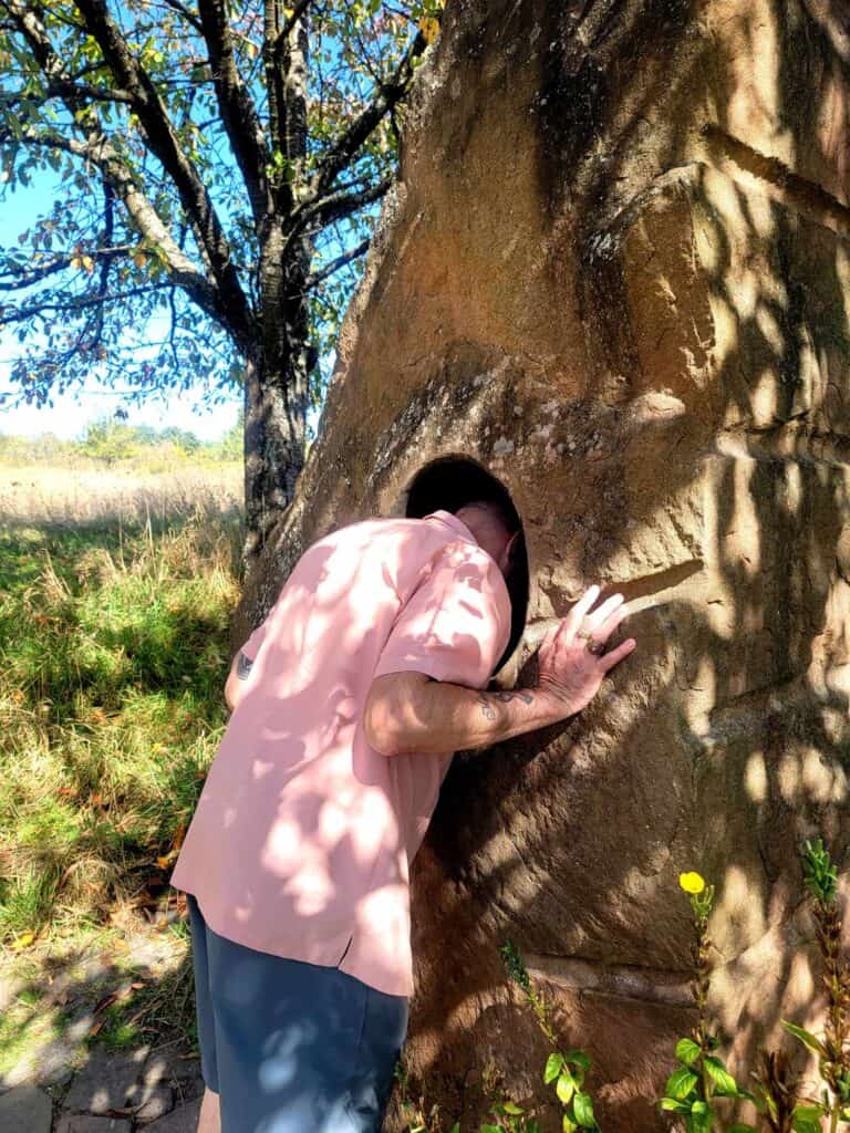 A man sticking his head into a "humming stone"