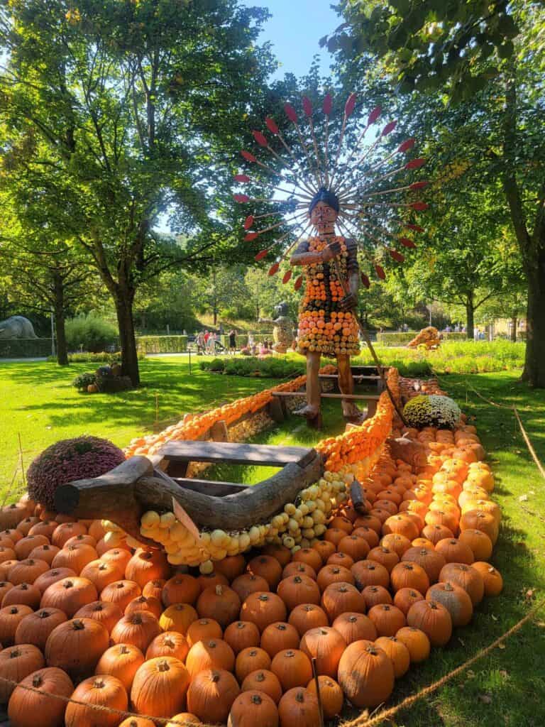 An Amazonian woman in a headdress paddling a boat, all made of pumpkins