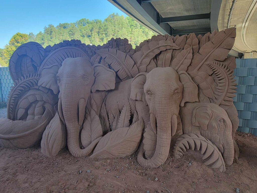 A large sculpted panel of elephants and leaves made of red sand