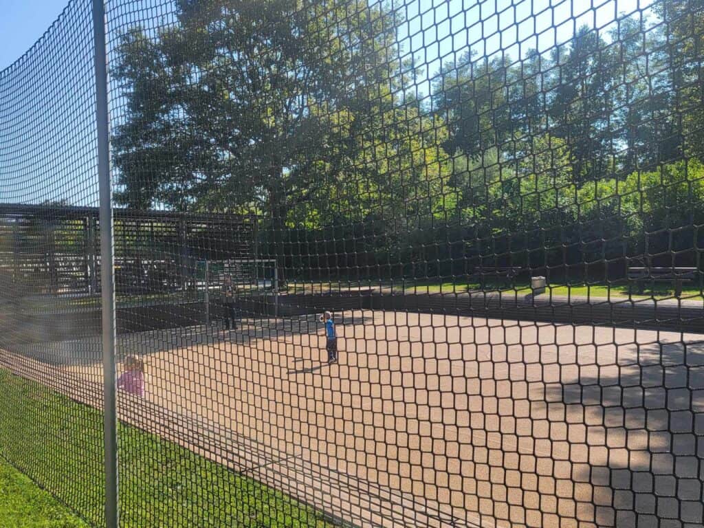 A man and his kid playing soccer behind a mesh fence