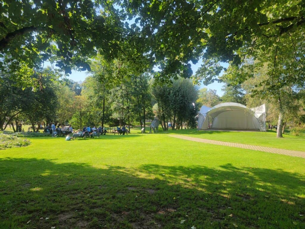 A large open green field surrunded by trees