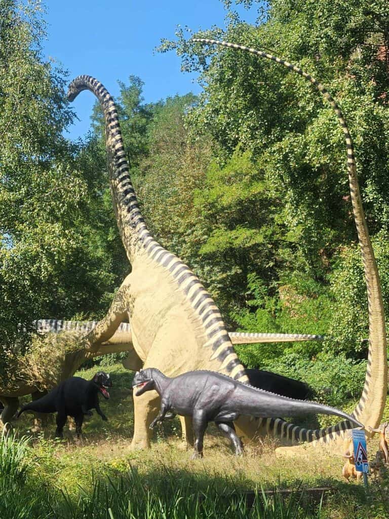 Several large dinosaurs with trees behind