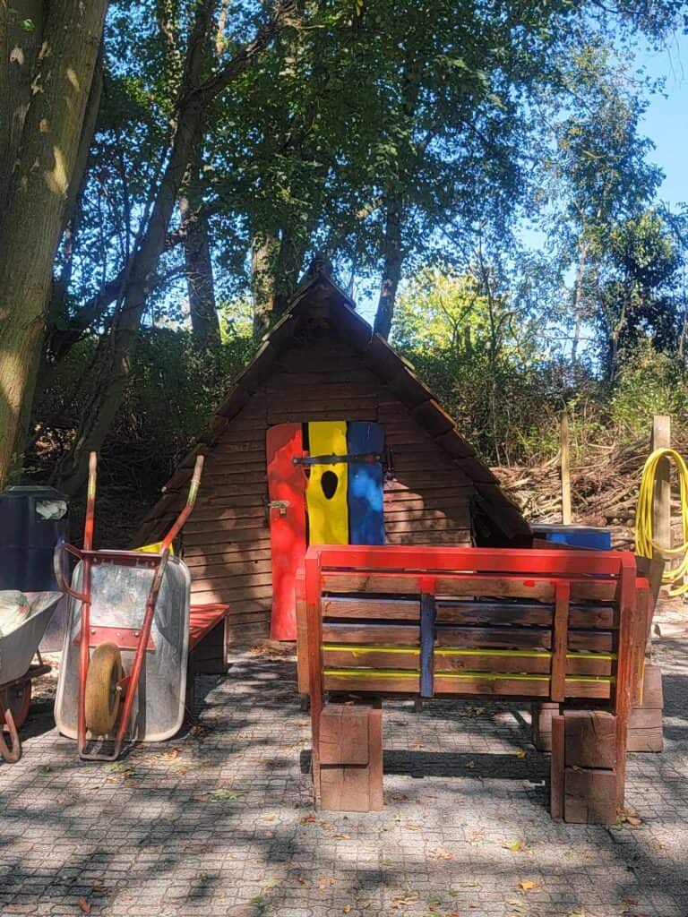 The "Witch's House" is triangular and made of wood with a door in red, yellow, and blue.