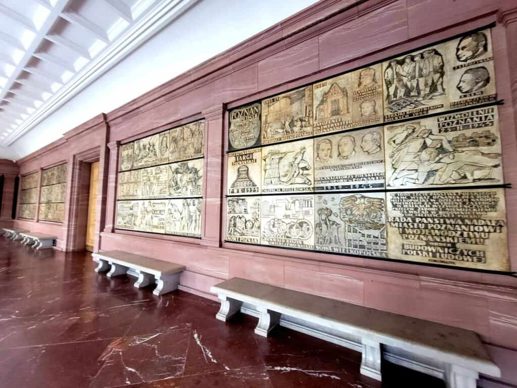 Low white marble benches underneath horizontal wooden panels carved with scenes from Poznan's history in mid-century Soviet style