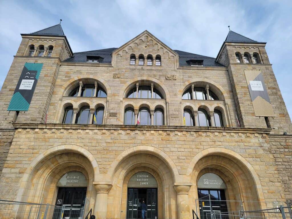 A pale limestone facade full of tiered arches. Over the door it says CENTRUM KULTURY ZAMEK.