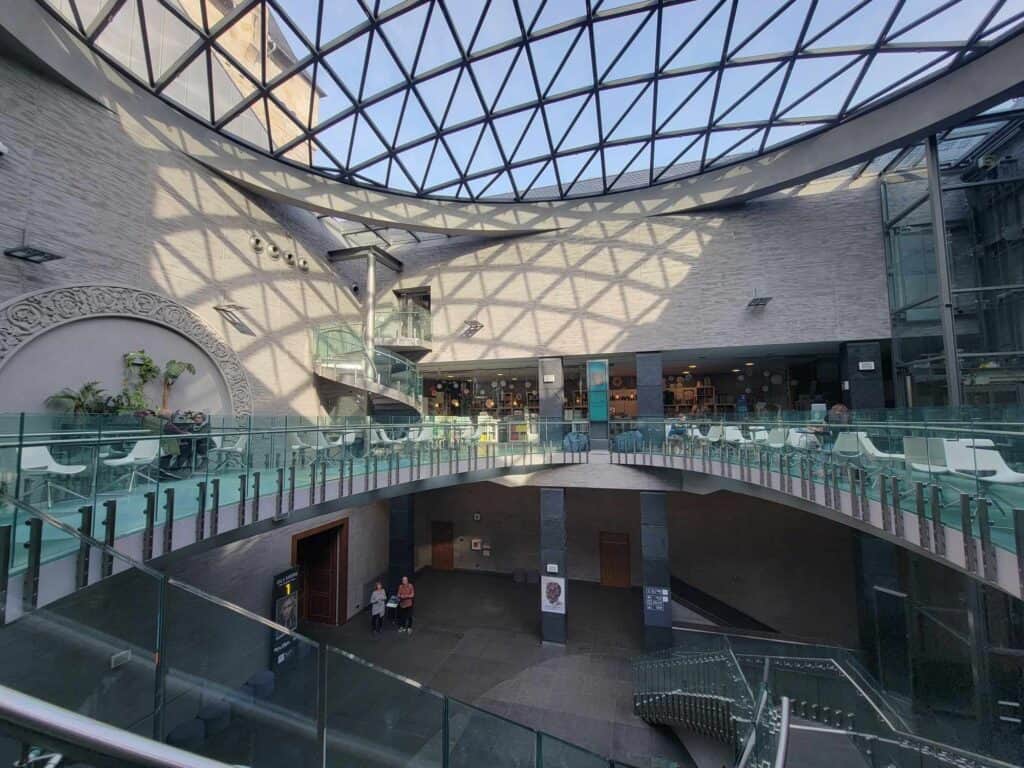 A huge round skylight with geometric forms overhanging a terrace skirting a large opening to the first floor