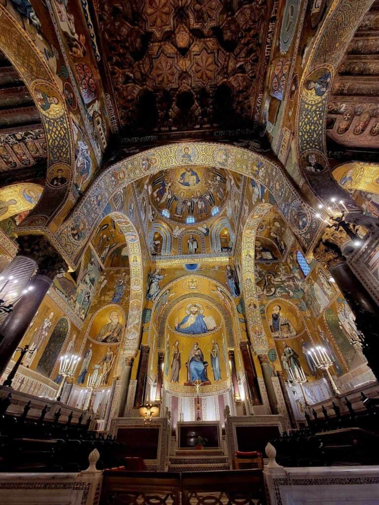 A chapel covered in gold, blue, and red mosaics of religious figures and geometric shapes