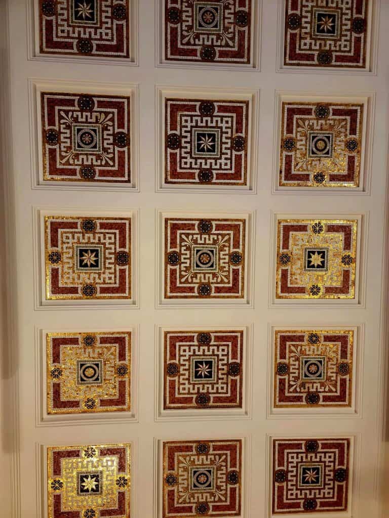 A ceiling with square mosaic tiles in dark red, dark blue and gold.