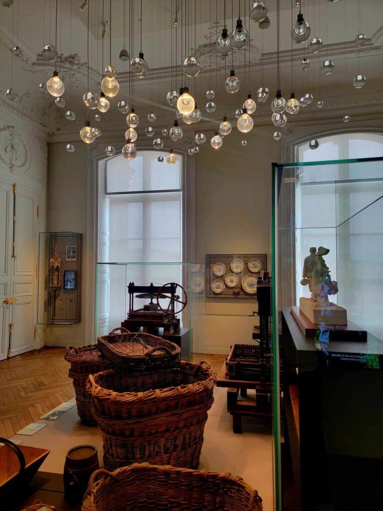 A room with baskets, an old wine press, and light fixtures hanging to look like bubbles