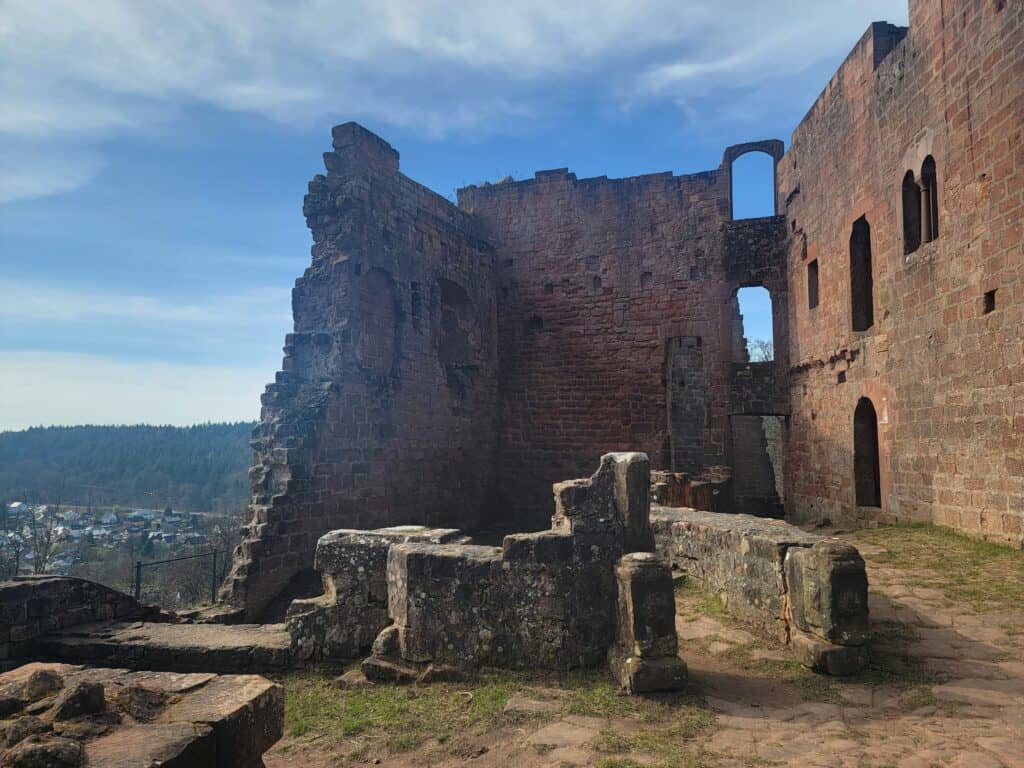 The tall walls of a castle ruin look out over a small village in the forest