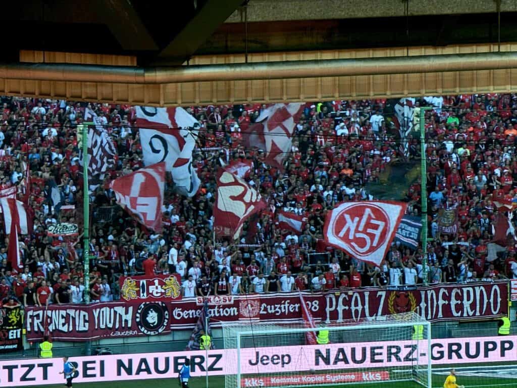 The WestKurve filled with fans waving huge flags with 1FCK in red and white