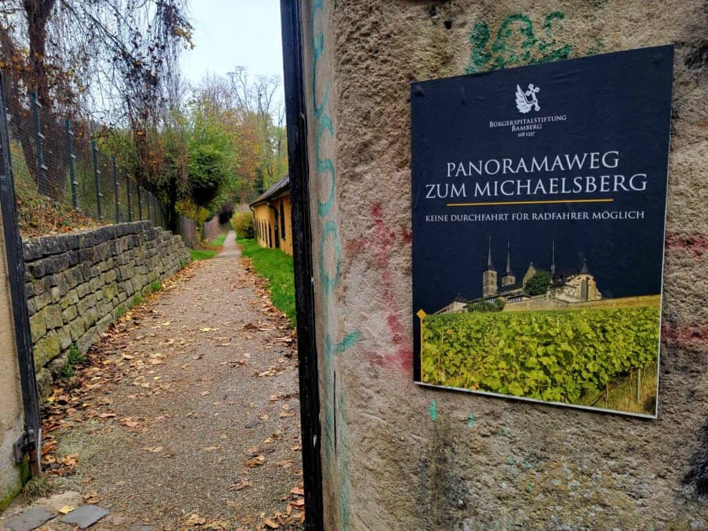 A doorway leading to a trail and a sign indicating the panoramic walk to Michelsberg