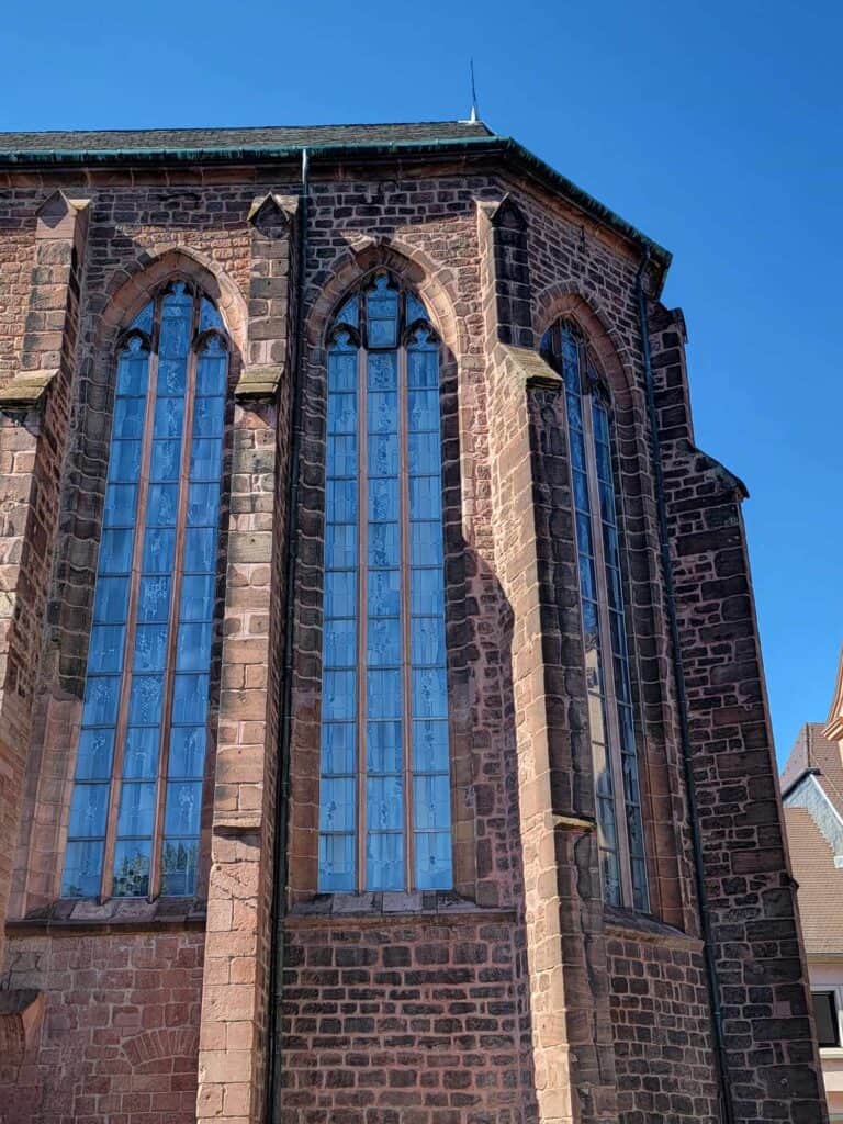 The outside of a church with high paned windows in a brick facade