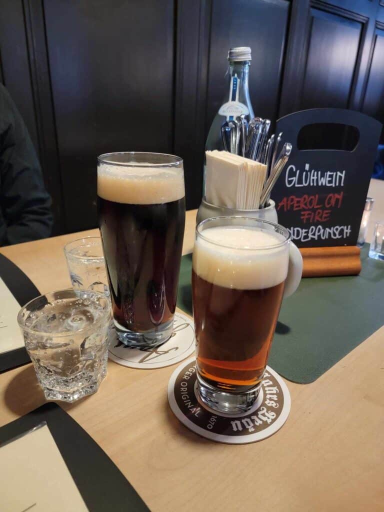 Two mugs of dark colored beer on a table 