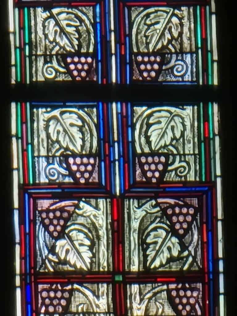 A panel of stained glass windows featuring grapes