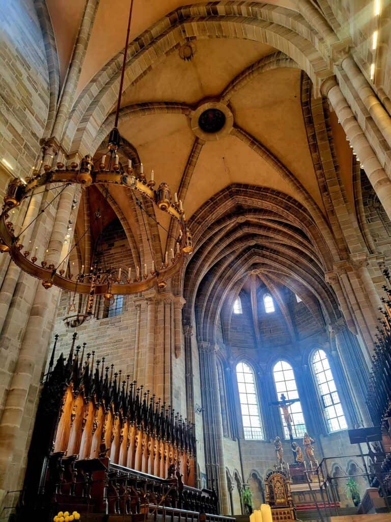 Huge round brass chandelier, and vaulted ceiling with high clear windows in the wall