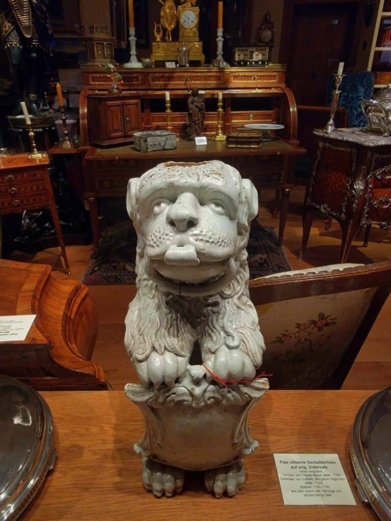 A white porcelain lion from the 18th century in front of antique wooden furniture