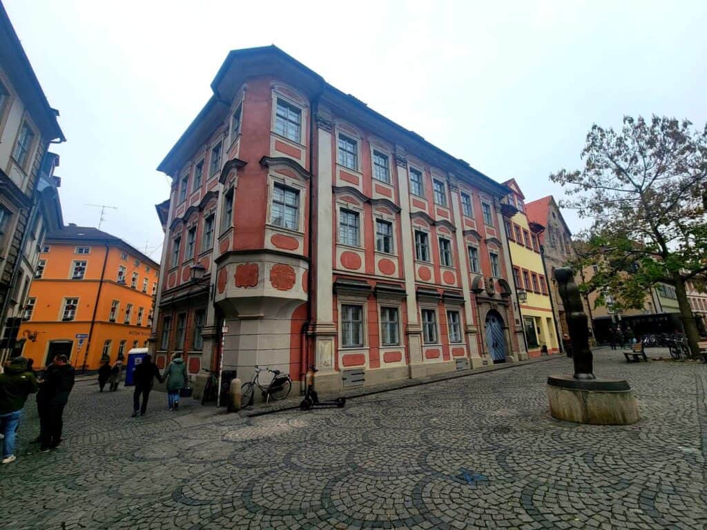 A large pink sandstone bulding with three stories of windows