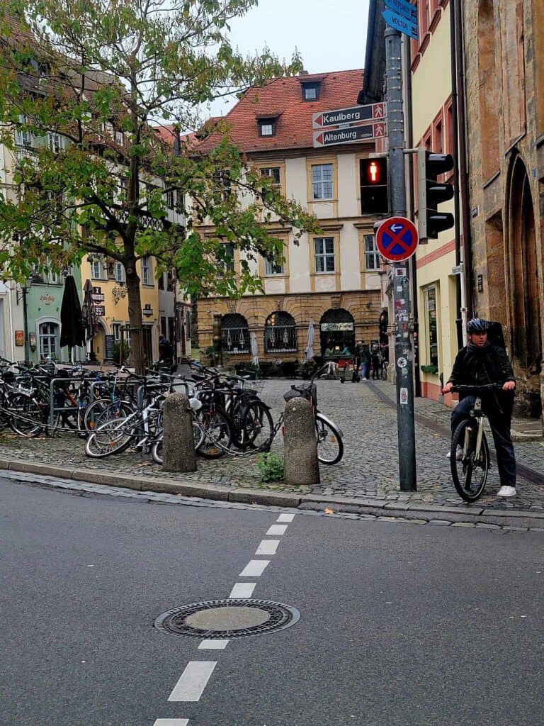 A large pile of bicycles in a cobblestone square, a man on a bike