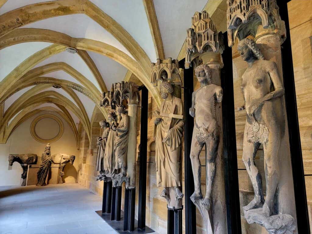 A line of stone statues of saints displayed in an arched gallery