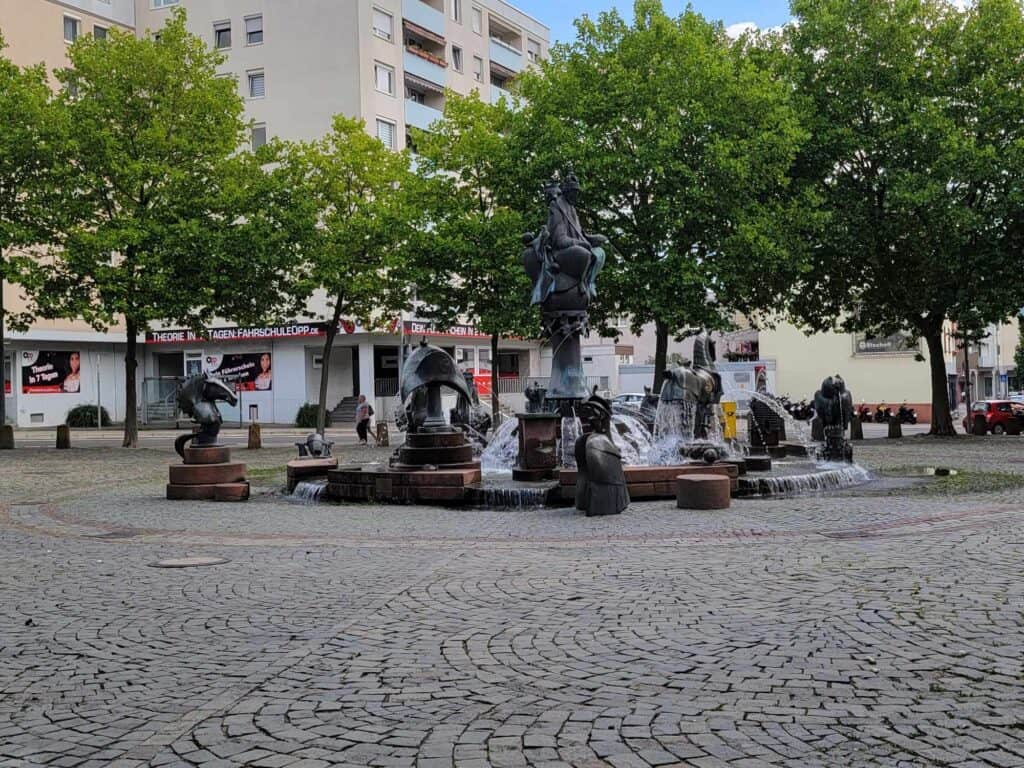 A large fountain with many figures on a cobblestone square