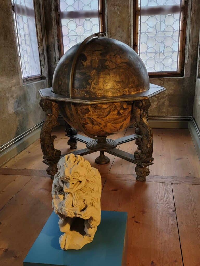 A 16th century leather globe and a stone medieval lion carving