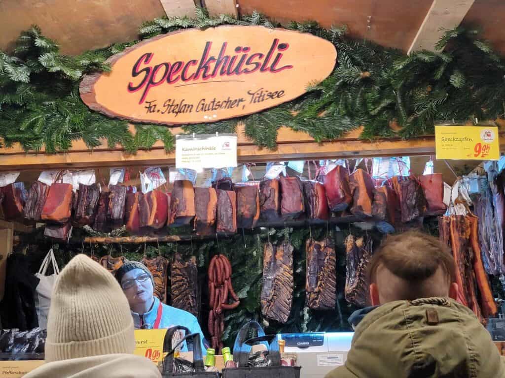 A Christmas market stall with a wooden sign saying Speckhüsli, Stefan Gutscher, Titisee