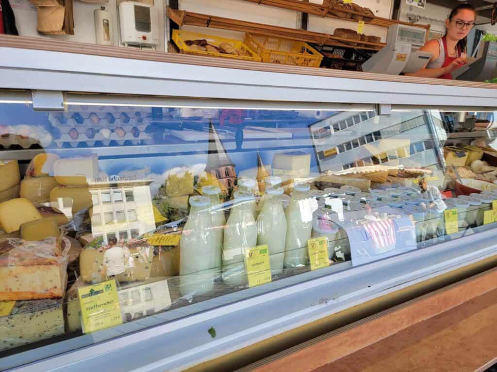 A refrigerated case filled with bottles of milk and various cheeses