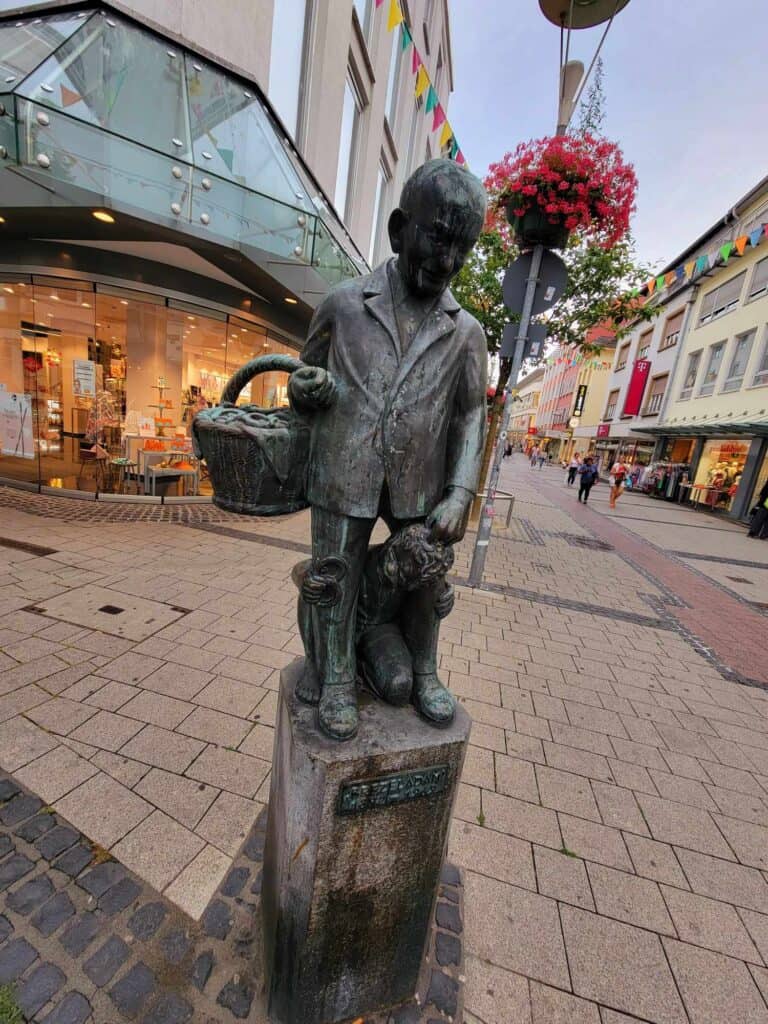 A bronze statue of a man carrying a basket of pretzels and a little boy at his feet