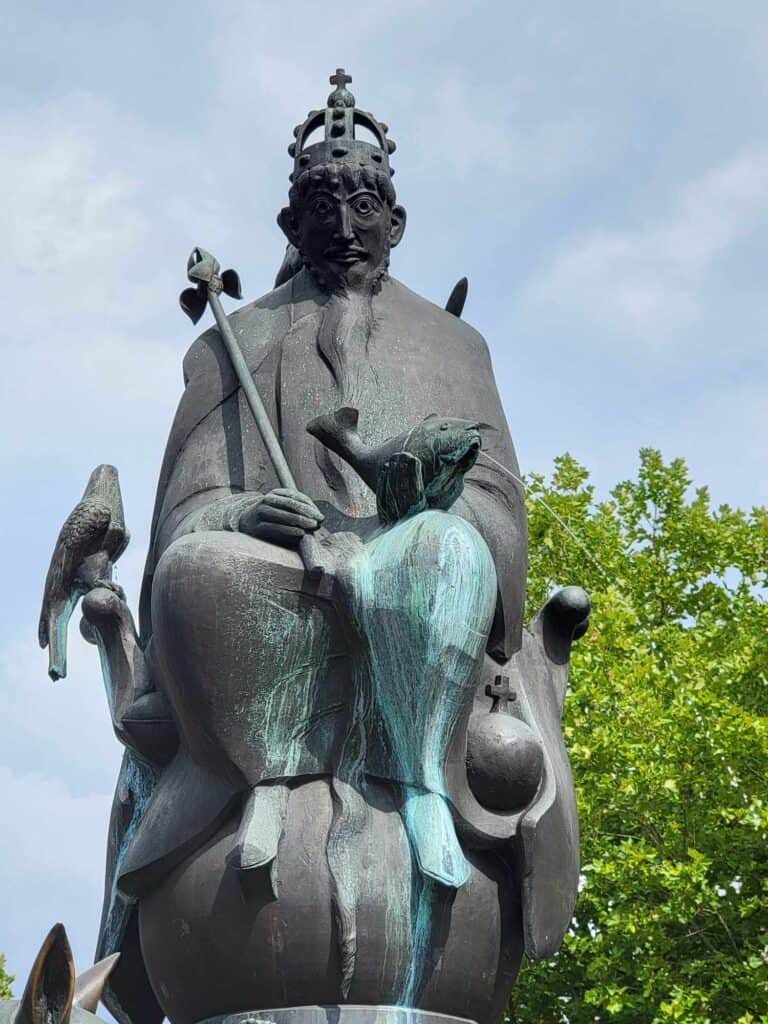 A large bronze of crowned Emperor Barbarossa holding a scepter with a carp in his lap