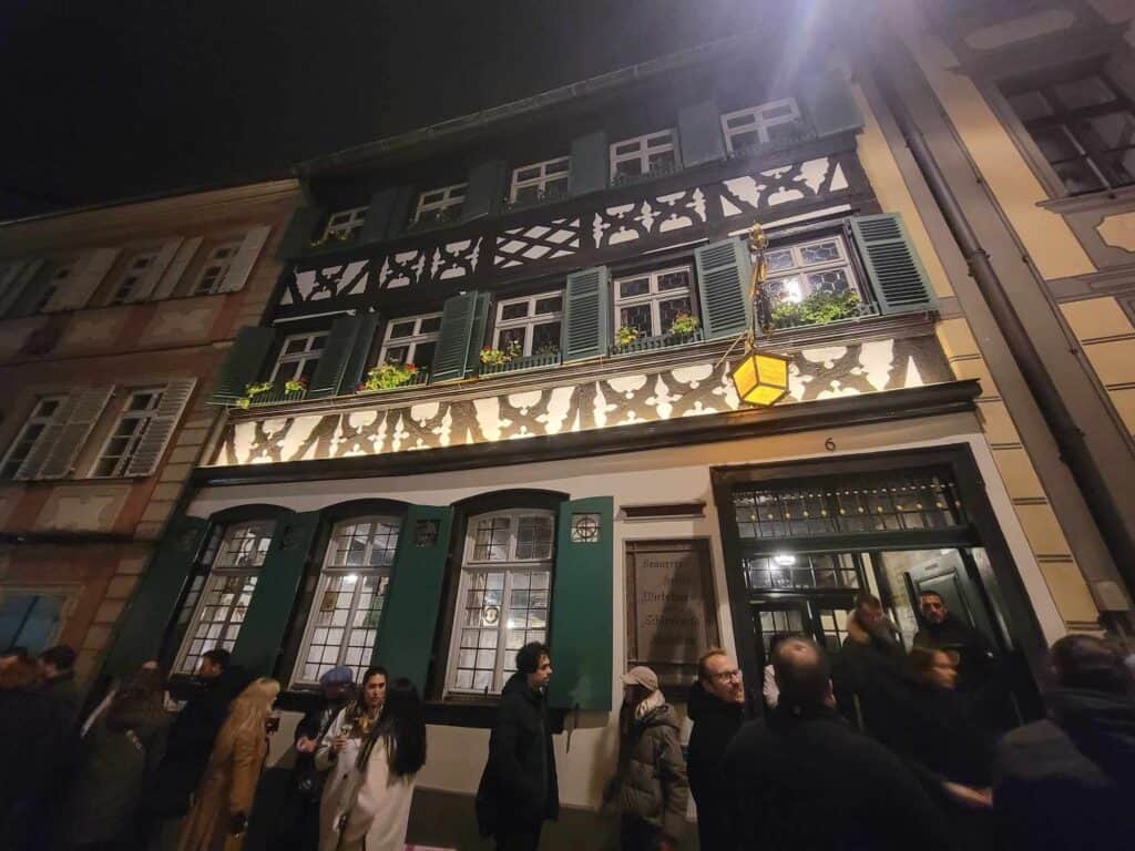 The ornate timbered facade of Scherlenka brewery, white with dark wood and kelly green shutters on the windows