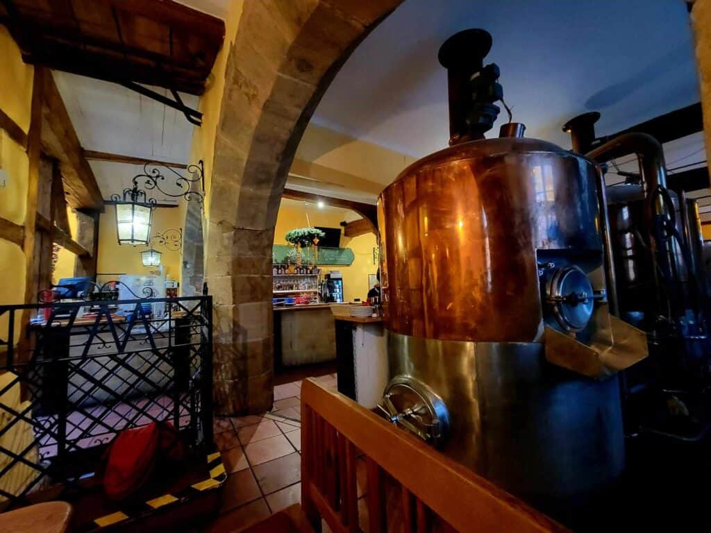 The interior of a brewery with a stone arch and large beer vat