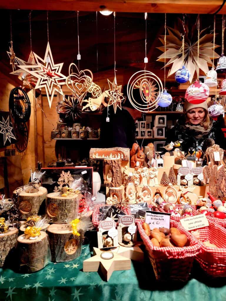 A booth full of wooden carvings, and hanging wooden mobiles and ornaments