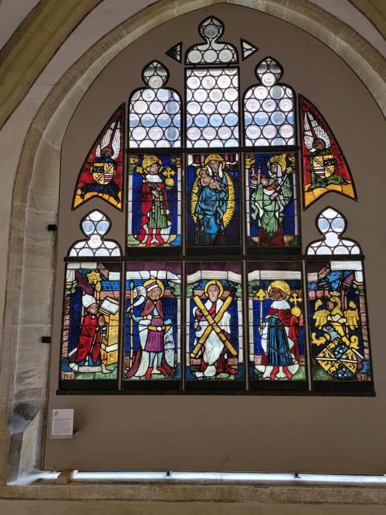 Deep jewel-toned stained glass window paned mounted in a stone archway