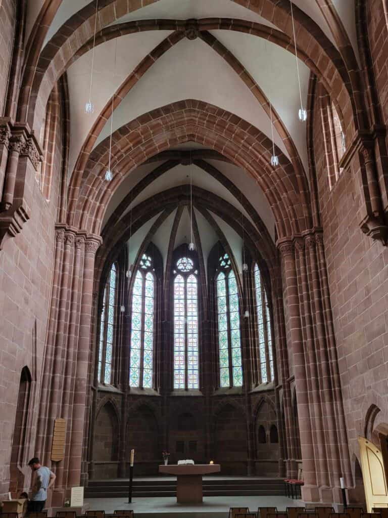 The arched interior of Stiftskirche with stained glass windows and a small altar