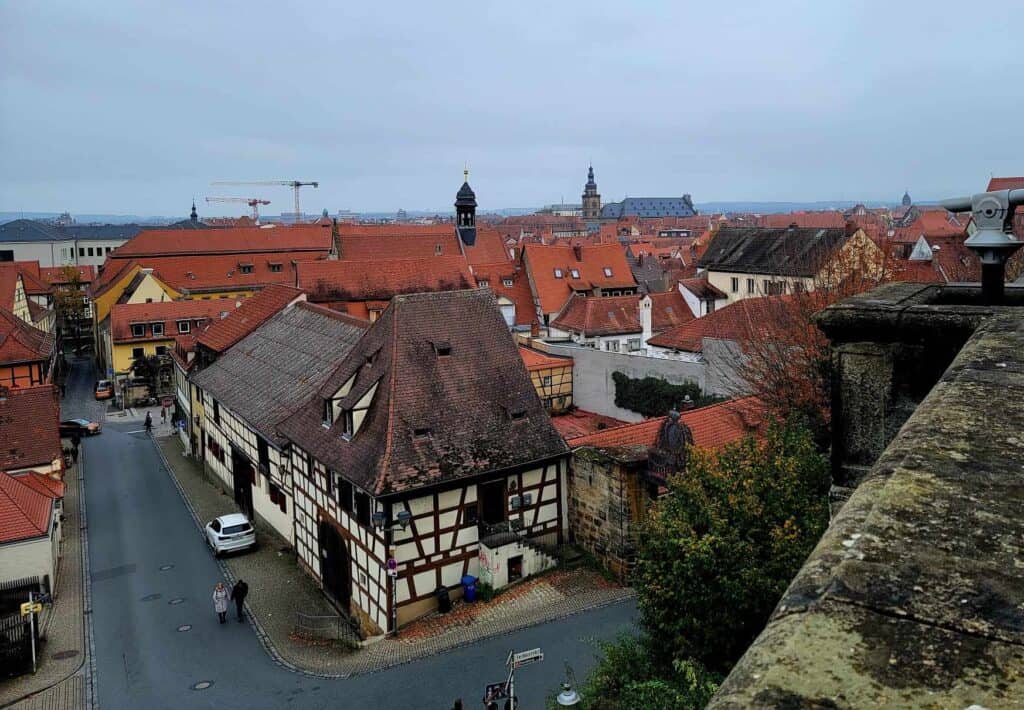 Looking down from a stone terrace on to Bamberg with a half timbered building and red roofs