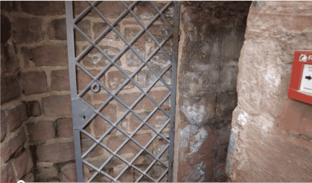 A latticed iron door with a lock embedded in a stone wall