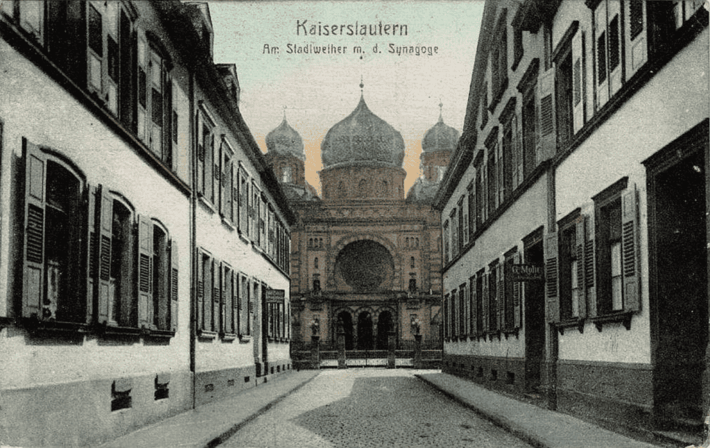 An old postcard, slightly colorized of the front of the old synagoge with its huge dome, flanked by two smaller ones and an arched entry with a rose window